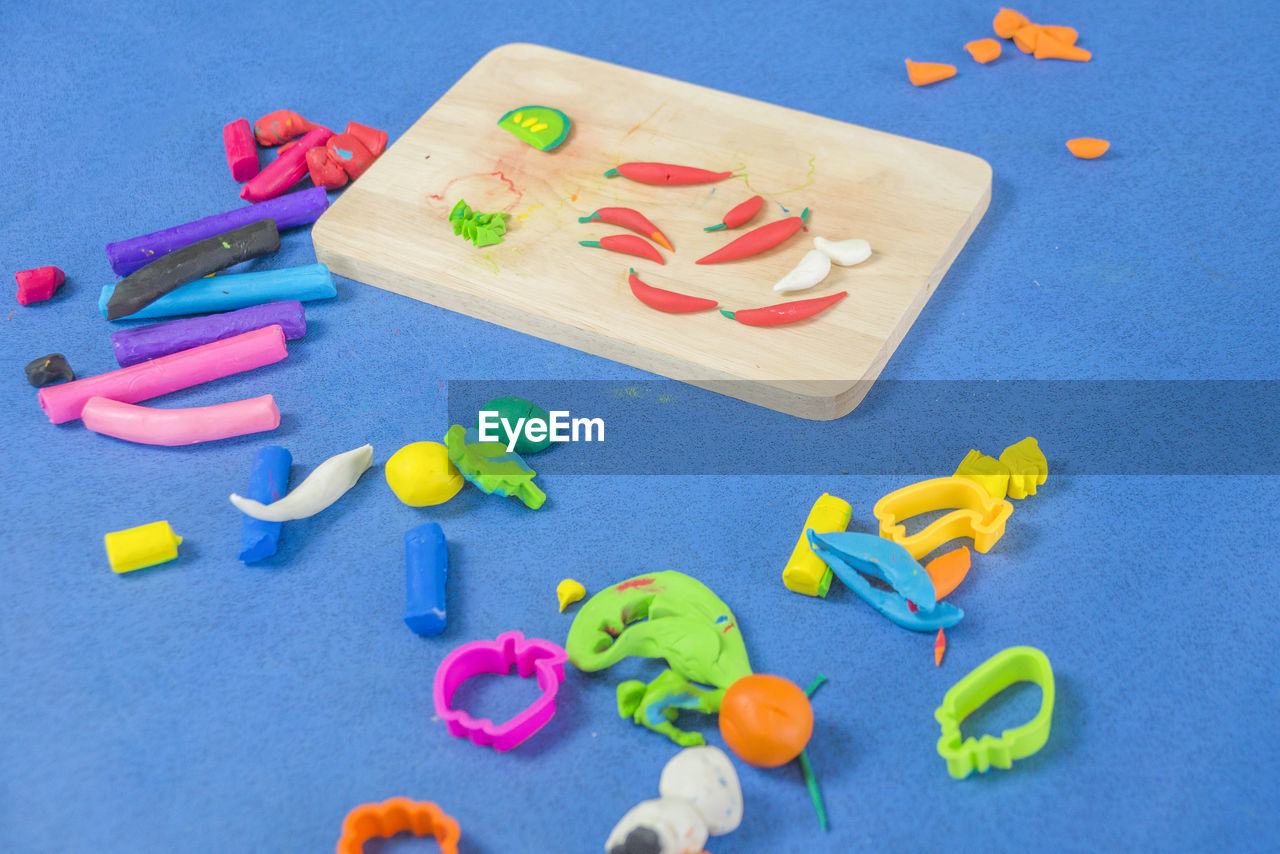 High angle view of multi colored clay toys on blue background