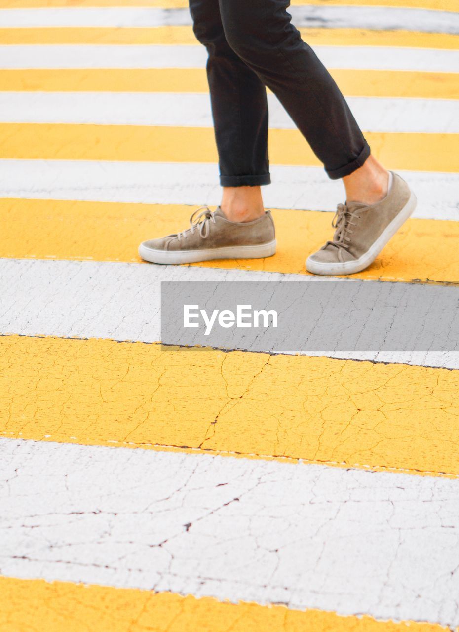 Low section of person walking on zebra crossing 