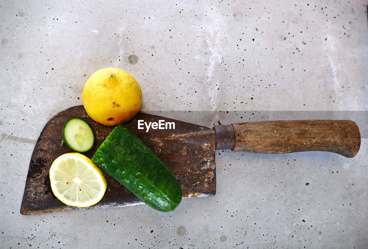 Directly above shot of lemons and cucumber on rusty axe