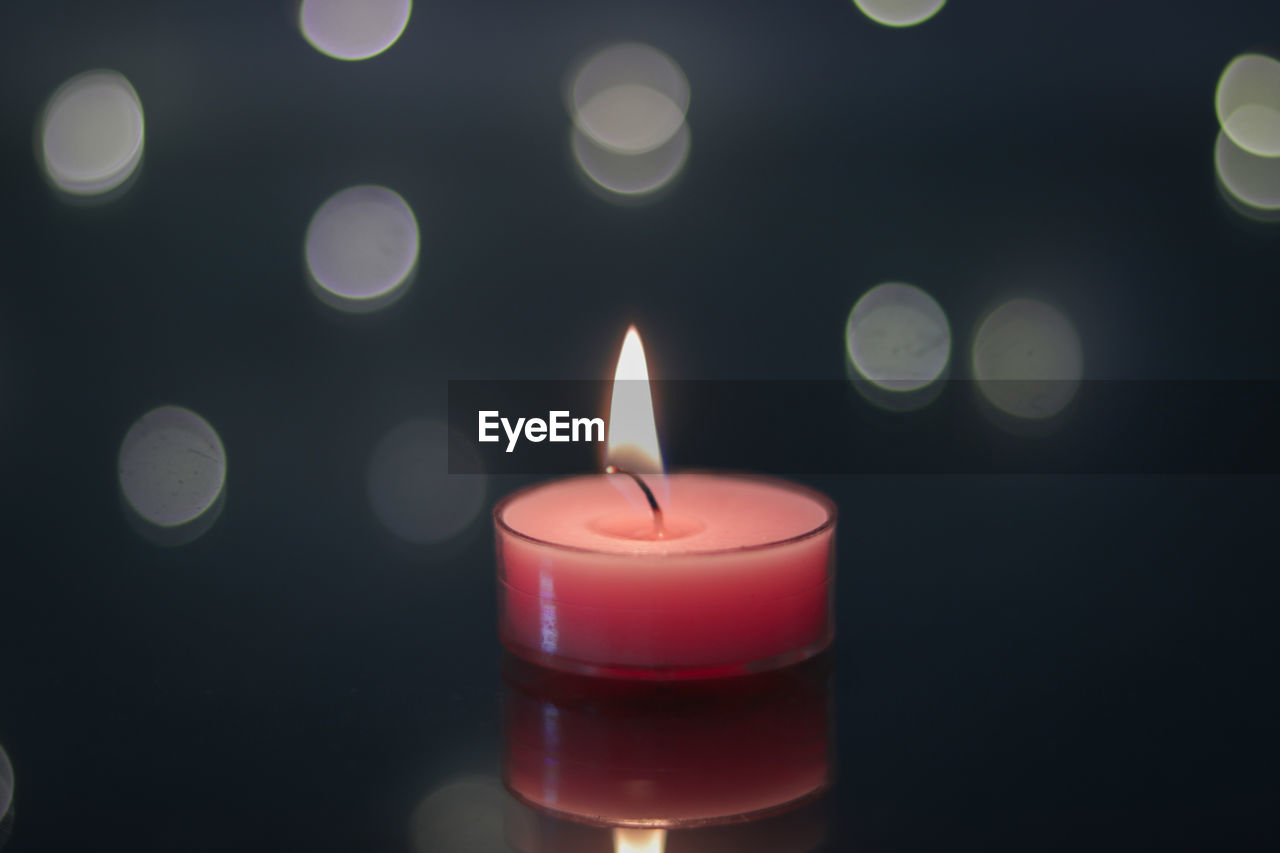 CLOSE-UP OF LIT CANDLE IN DARK