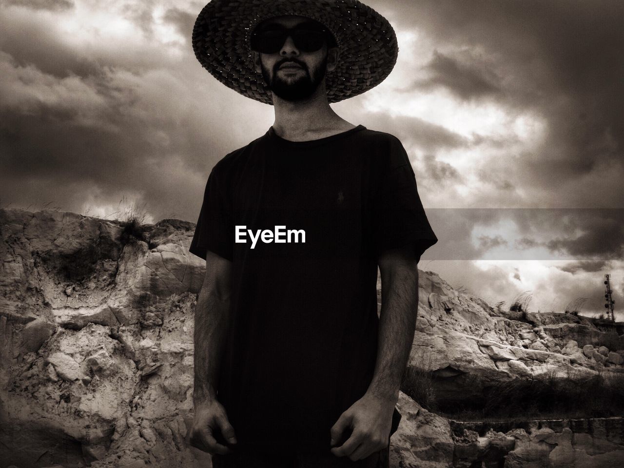 Low angle view of man wearing hat standing against cloudy sky during sunset