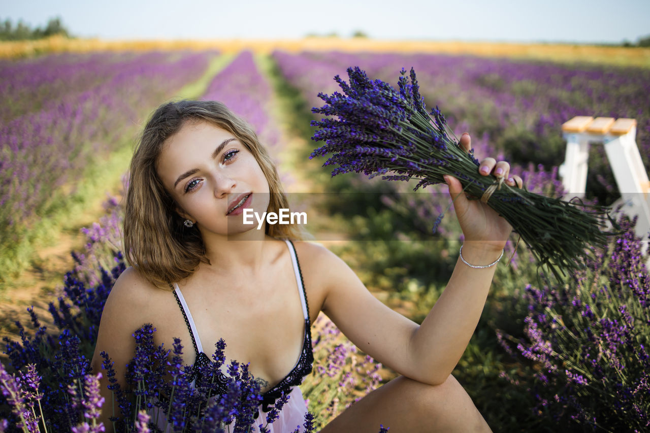 Portrait of young blonde woman enjoying lavender field.
