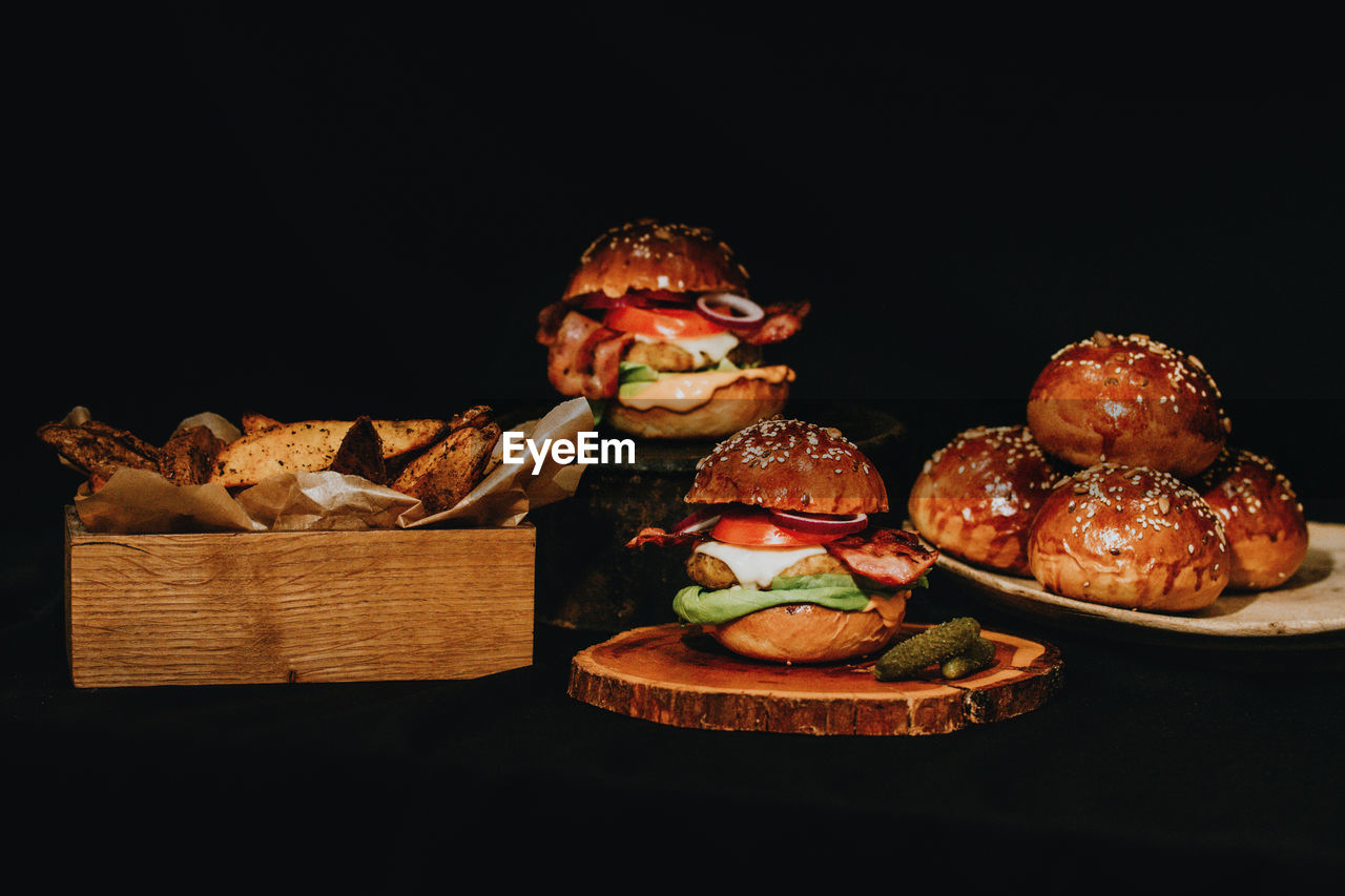 Close-up of burgers with chips against black background