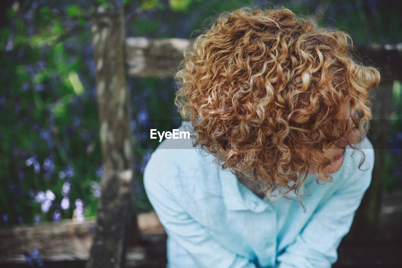 Close-up of woman with curly short hair sitting on bench