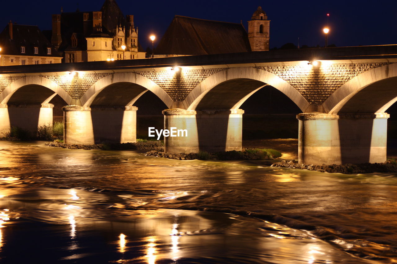 Bridge over river against sky at night