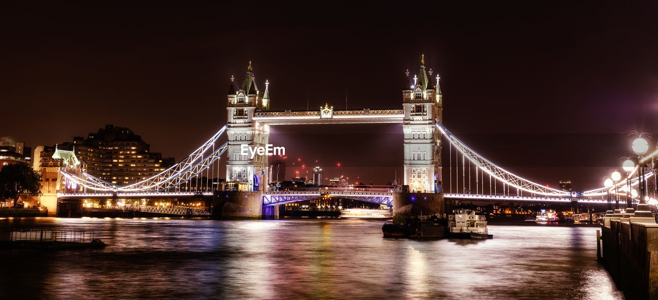 Illuminated bridge over river at night