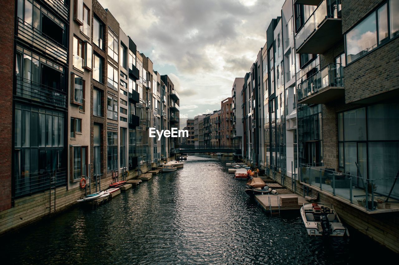 Canal amidst buildings in city against sky