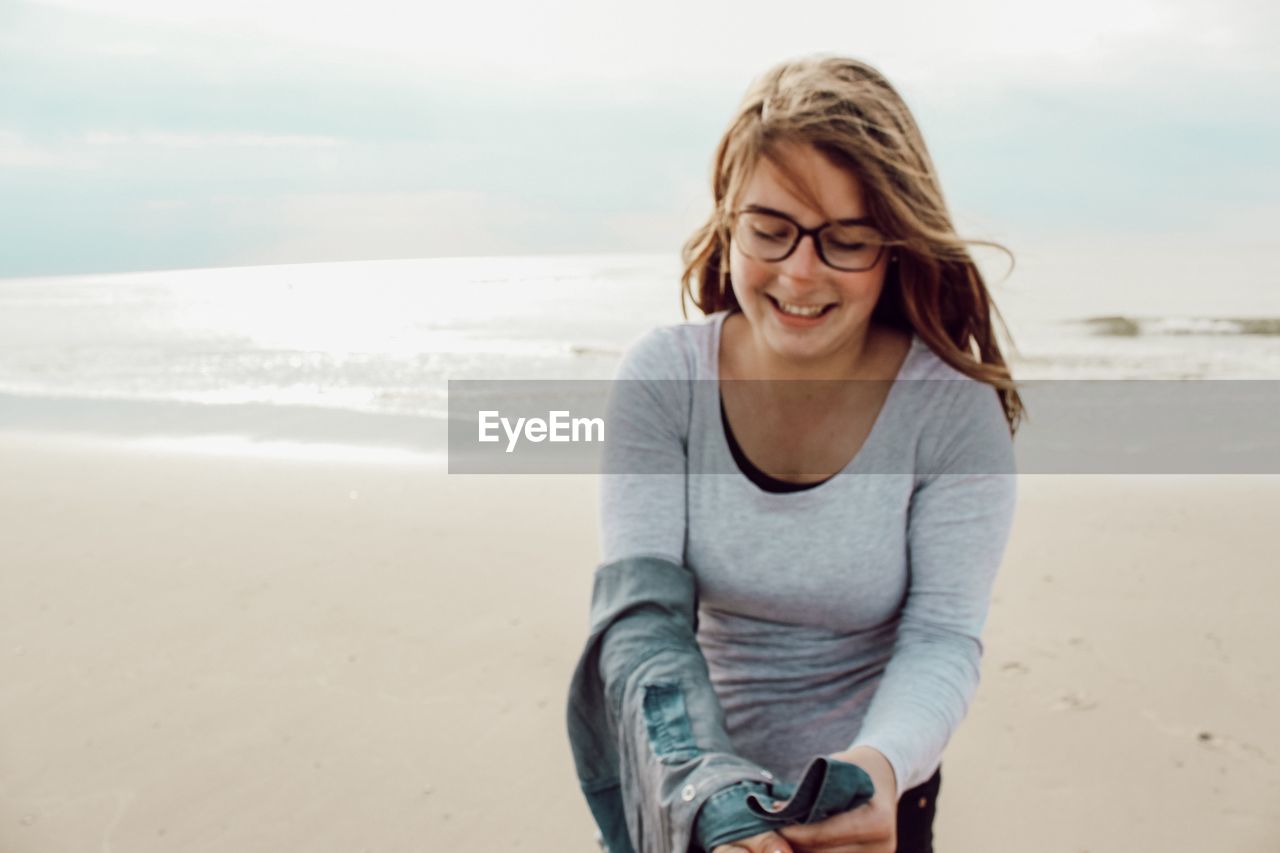 Beautiful young woman on beach against sky