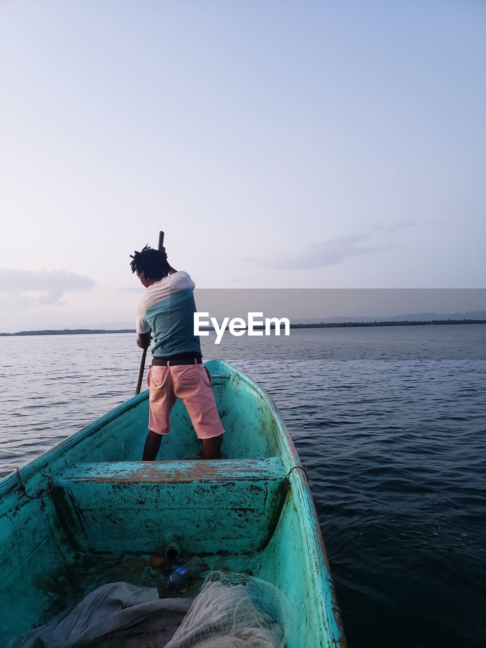 Rear view of man sitting on boat in sea against sky