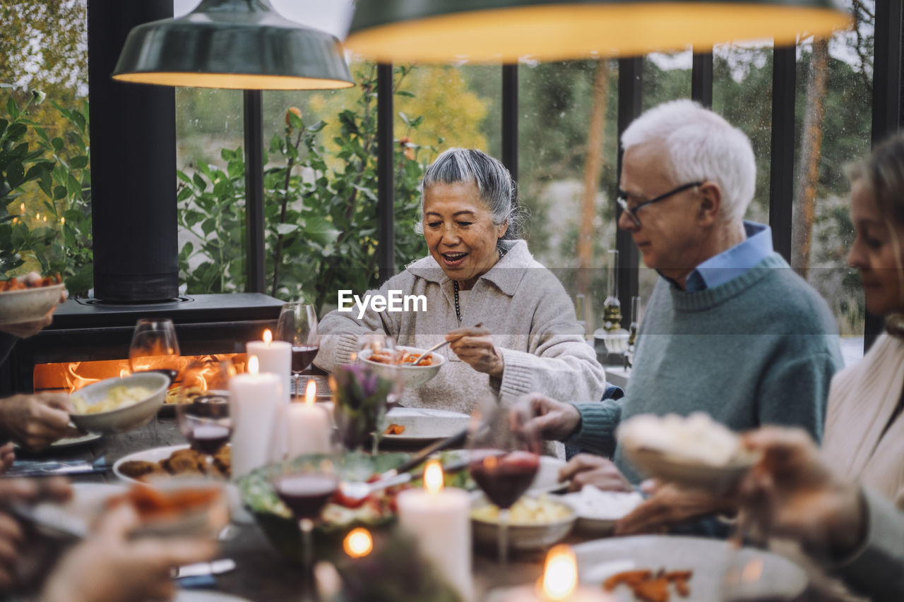 Senior woman serving food to male friend at dinner party