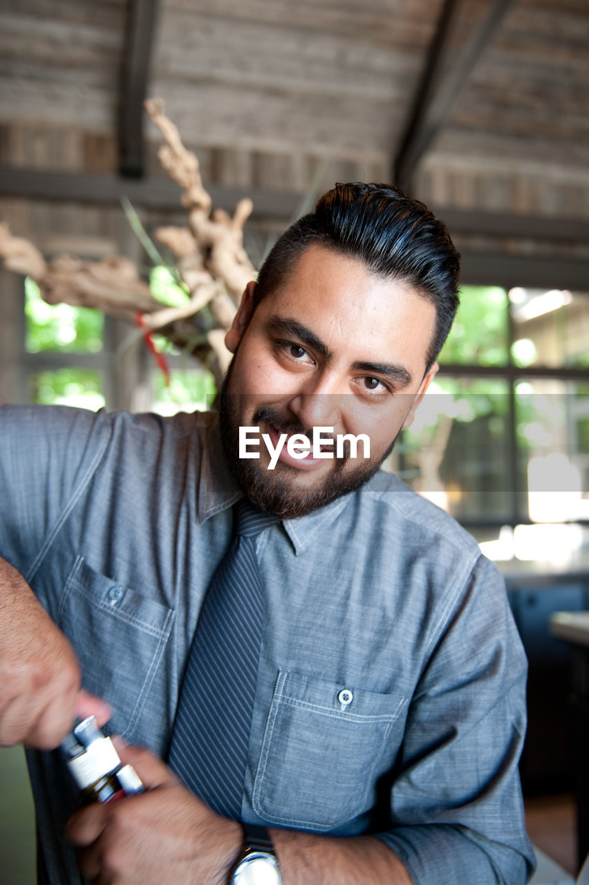 Portrait of bartender opening bottle in bar