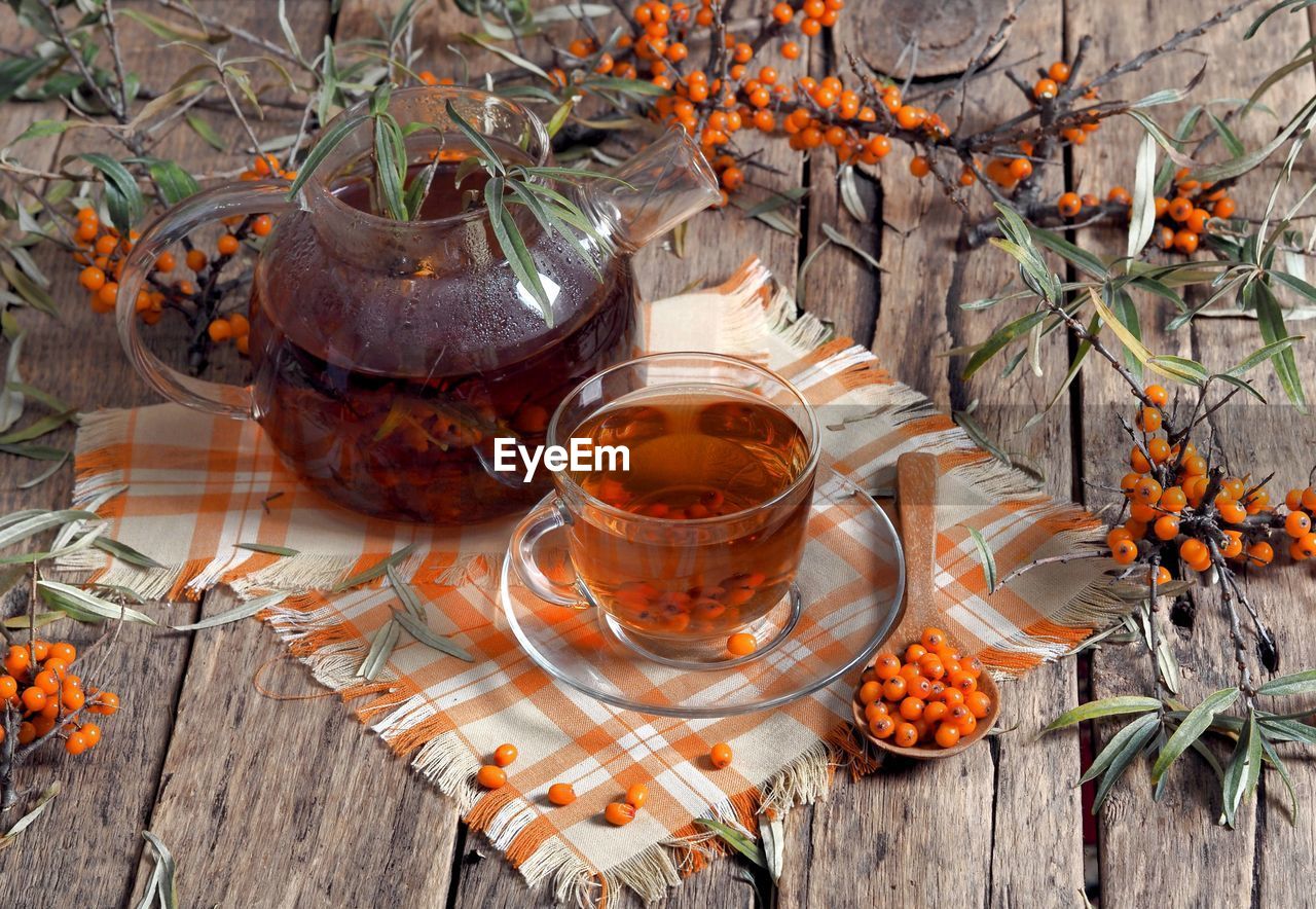 Branches of sea buckthorn, herbal tea with sea buckthorn and jam on a wooden natural background. 