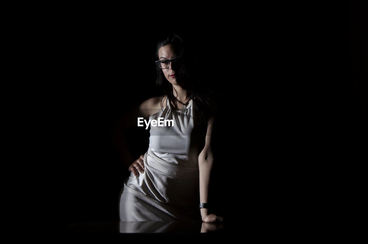 Young woman in dress standing against black background