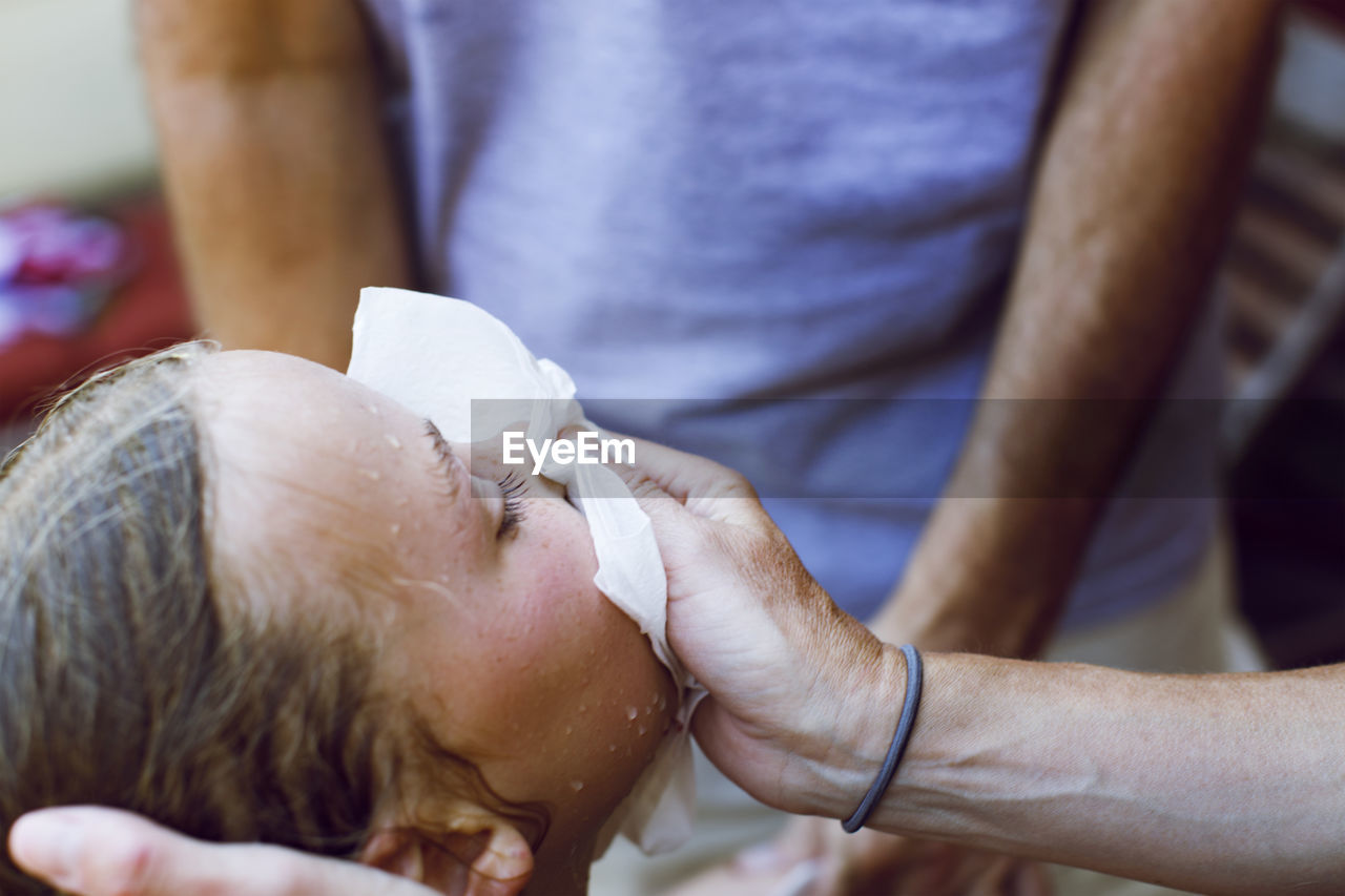 Cropped image of man covering girl's bleeding nose