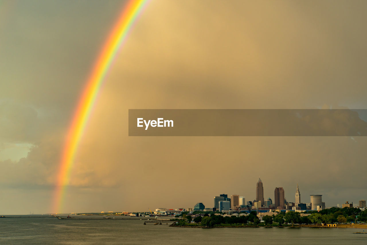 Scenic view of rainbow over sea against buildings
