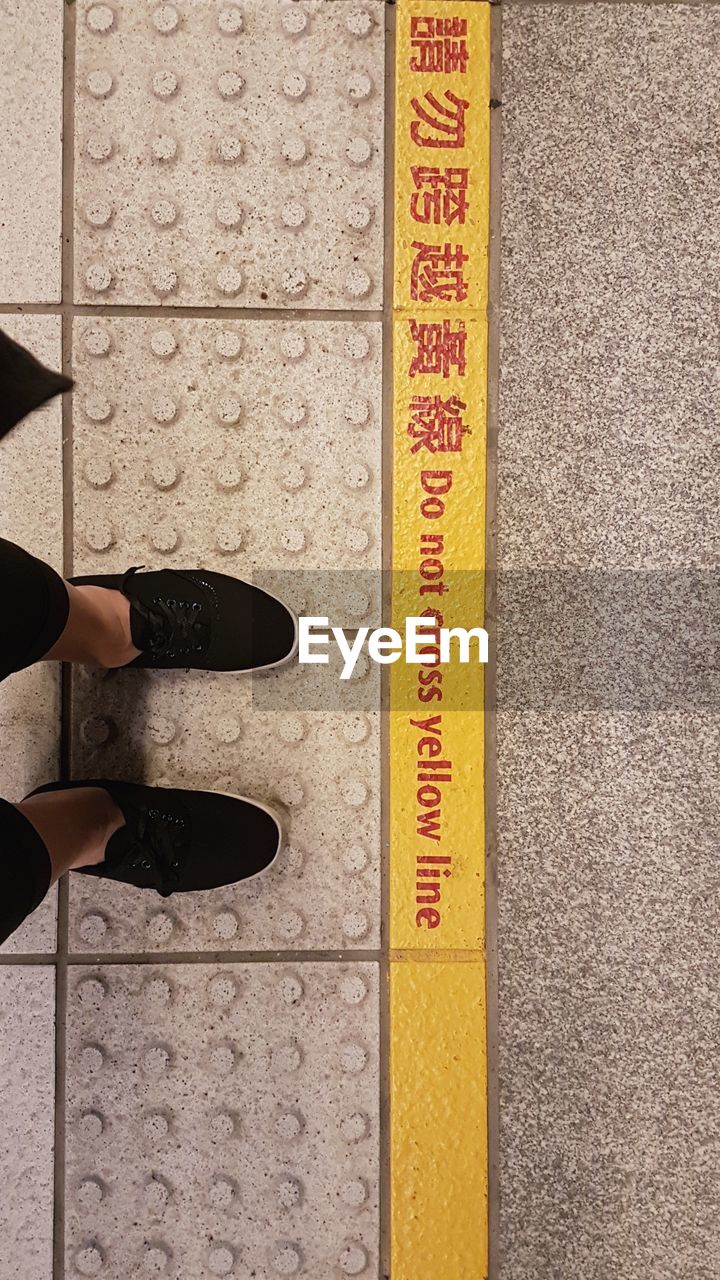 Low section of person standing by text on railroad station platform