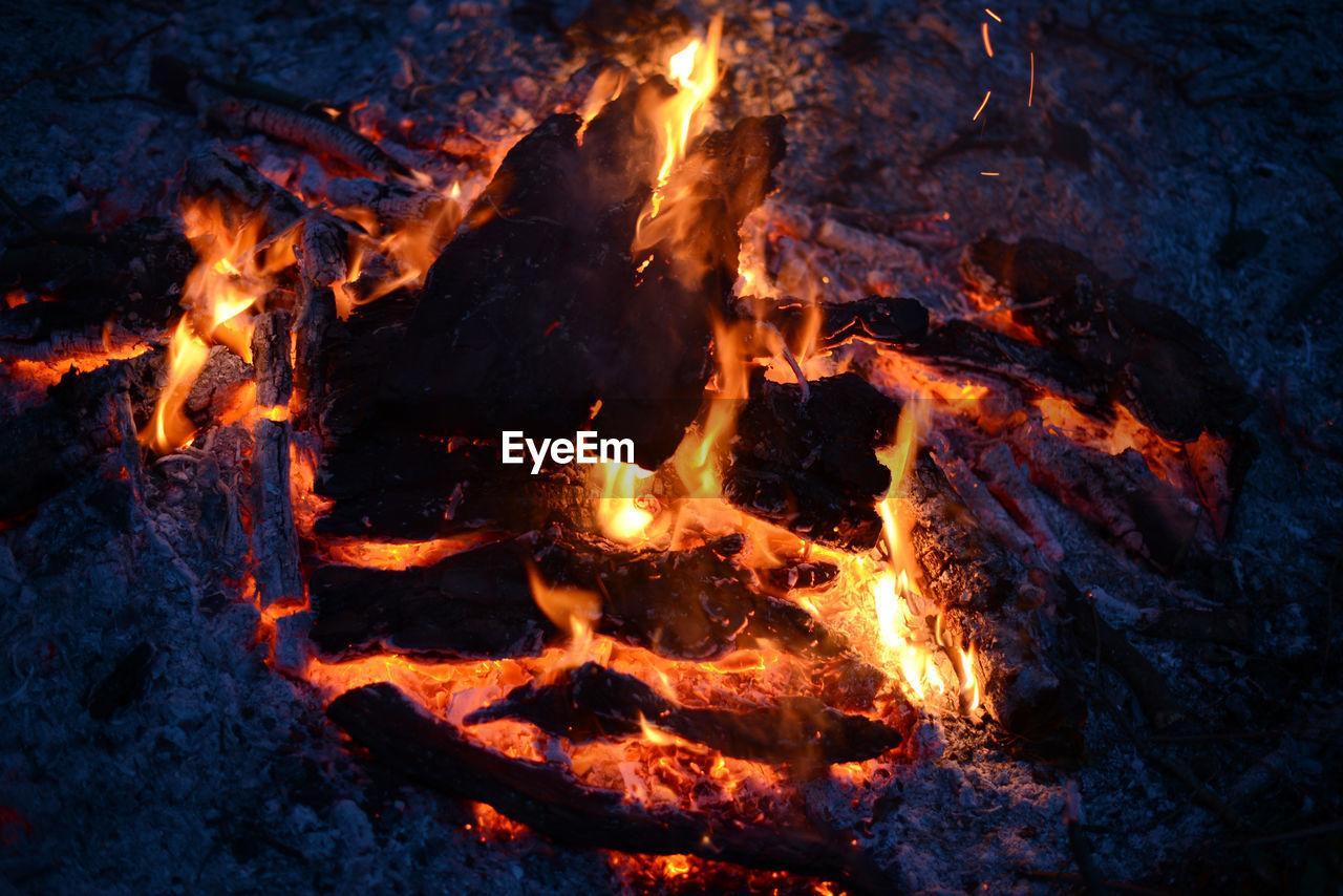 HIGH ANGLE VIEW OF FIRE BURNING IN THE DARK