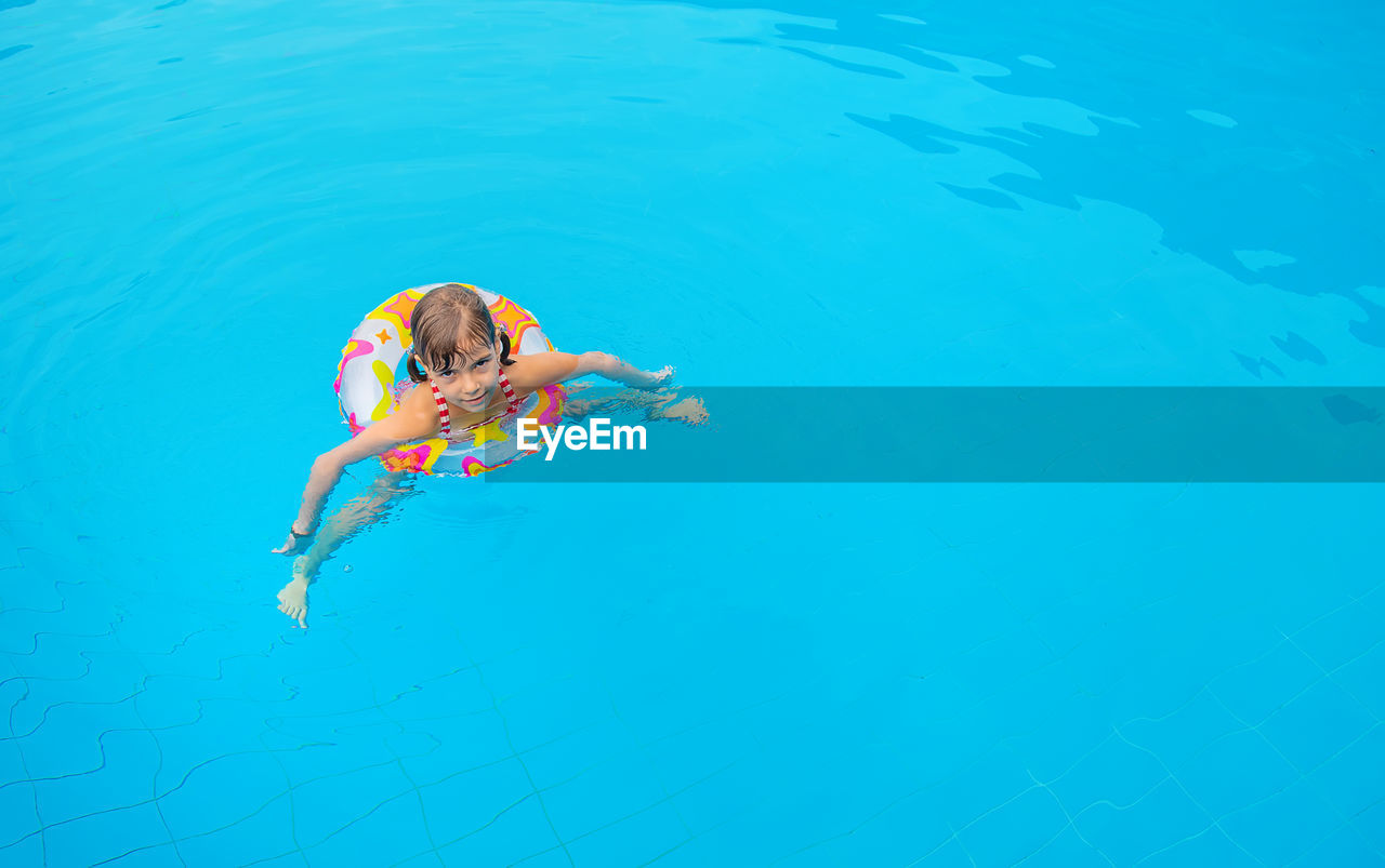 High angle view of girl swimming with inflatable ring in pool