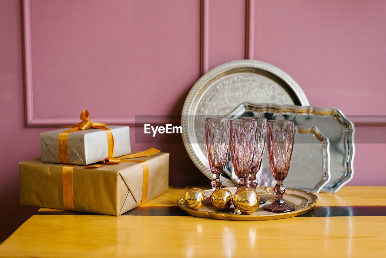 Pink glass glasses, gift boxes, christmas tree wreath, metal trays in the pink kitchen. christmas