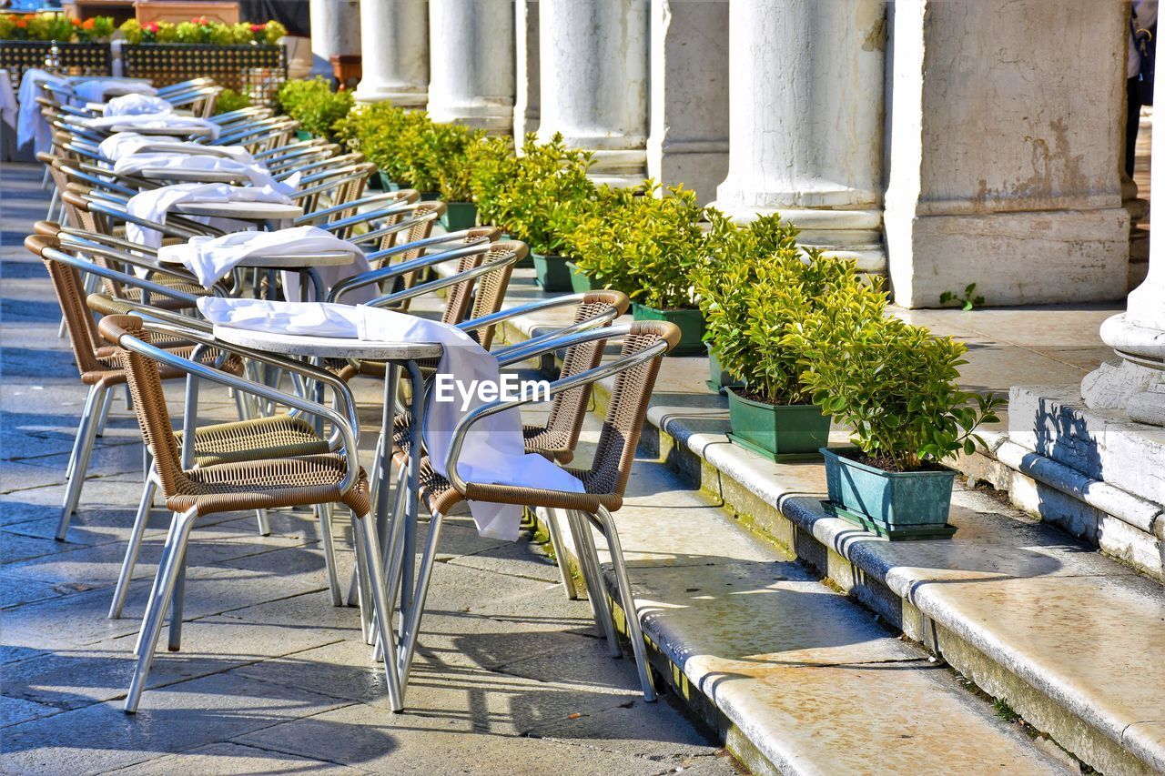 Empty chairs and tables against building