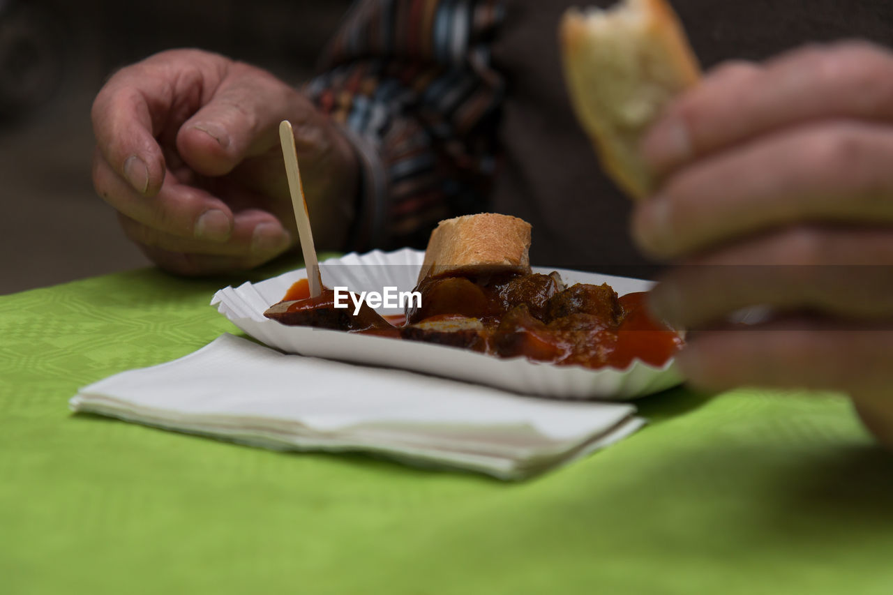 Close-up of hand with food in plate at table