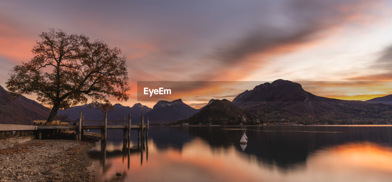 SCENIC VIEW OF LAKE AND MOUNTAINS AGAINST ORANGE SKY