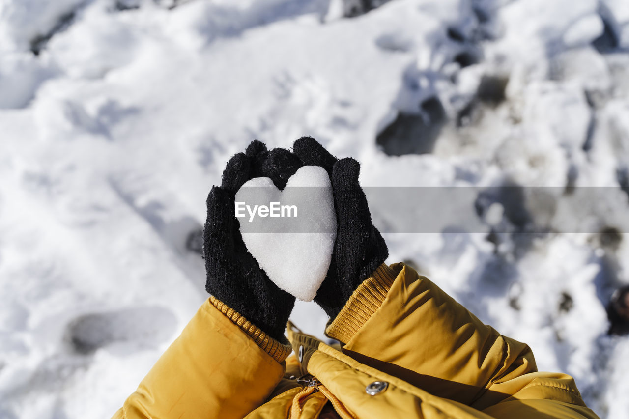 Girl's hands holding heart shaped snow in park
