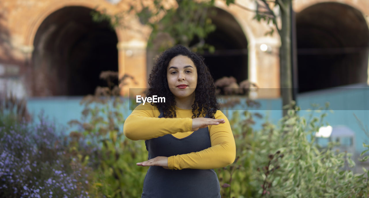 Portrait of woman gesturing while standing against plants