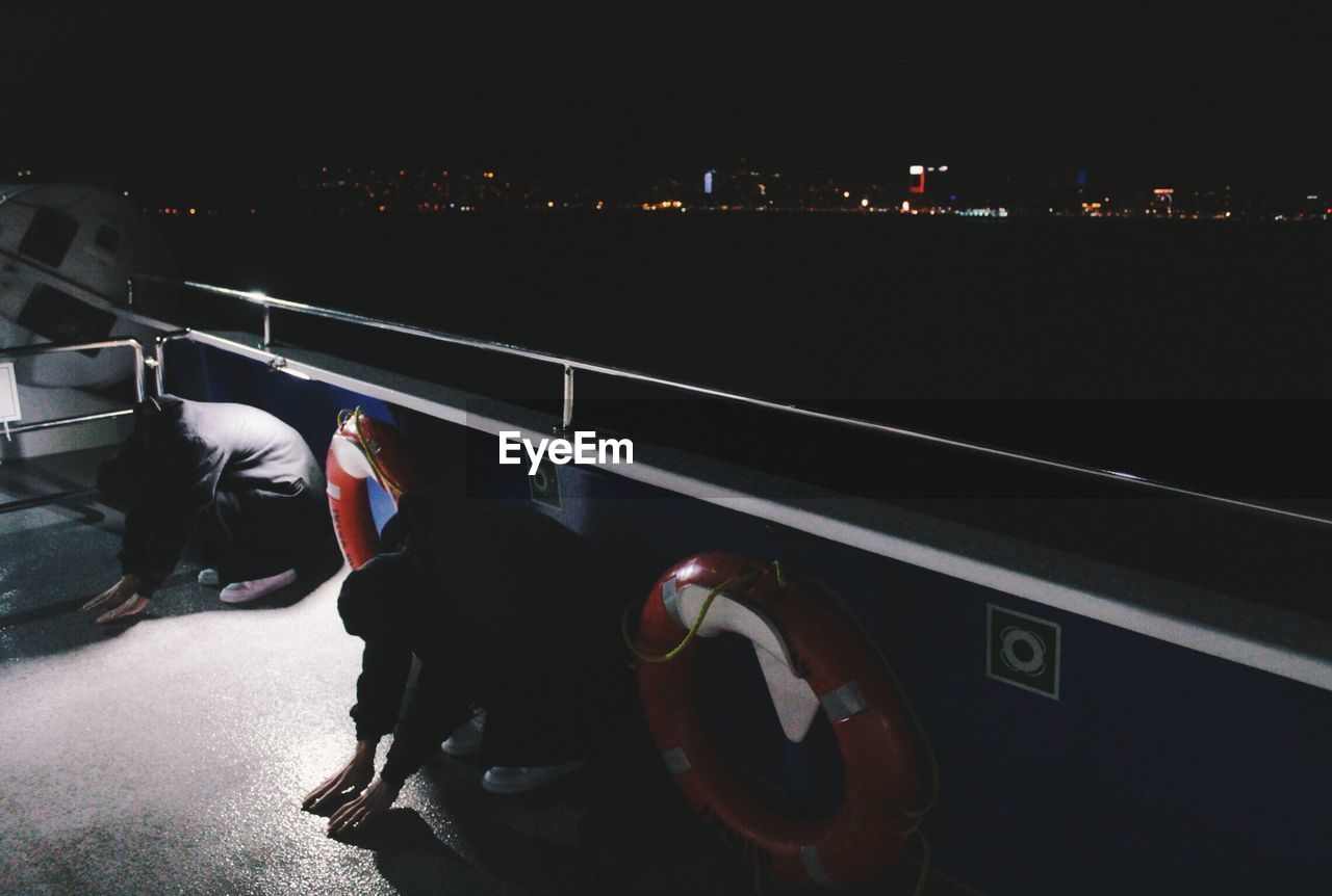 LOW SECTION OF MAN WITH ILLUMINATED LIGHTS AT NIGHT