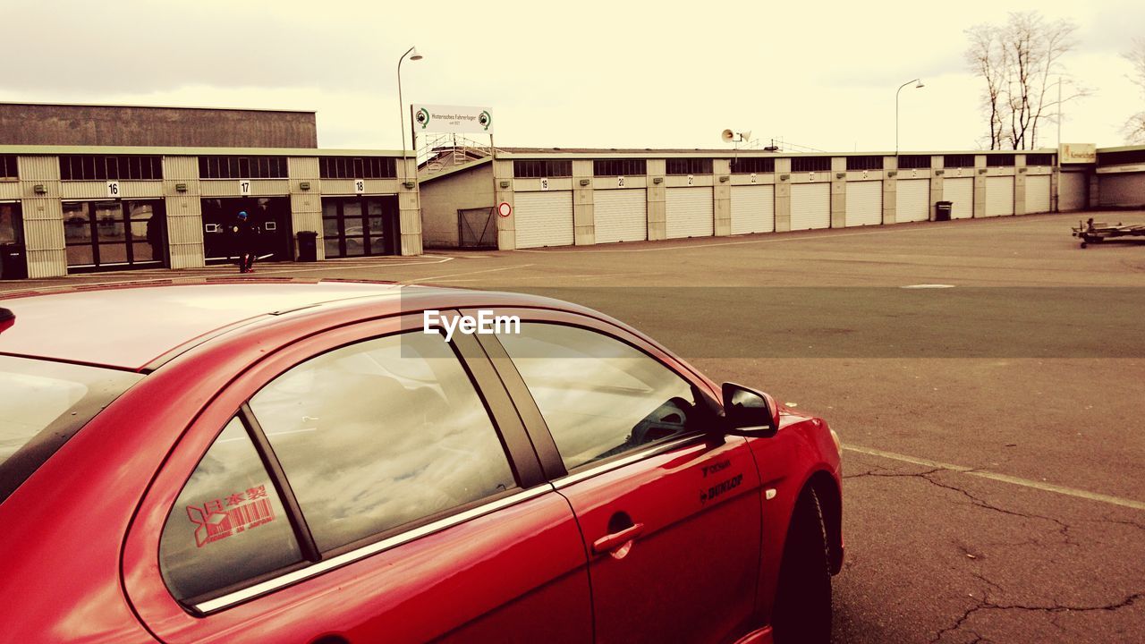 CARS ON ROAD BY BUILDINGS AGAINST SKY