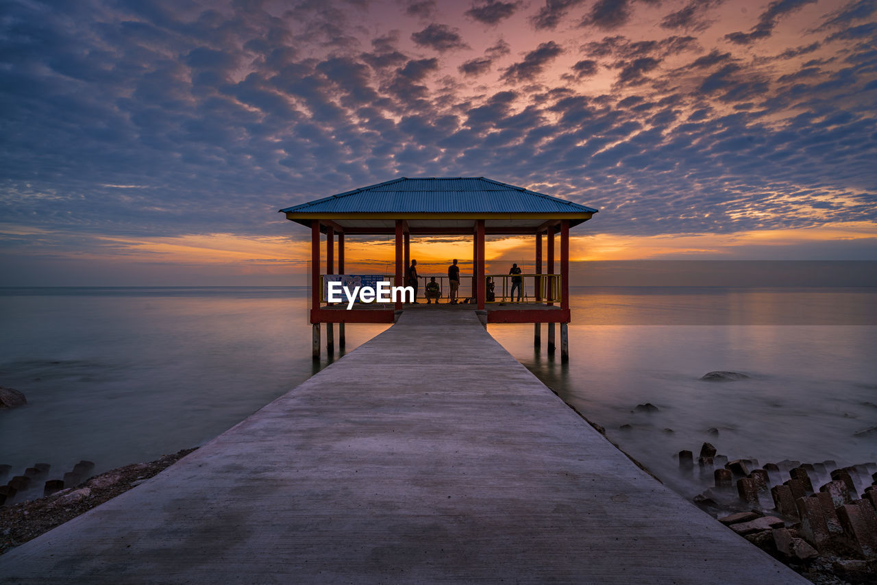 LIFEGUARD HUT ON PIER AGAINST SKY DURING SUNSET