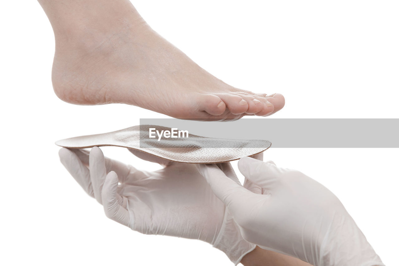 Cropped hand of doctor holding insoles by patient feet