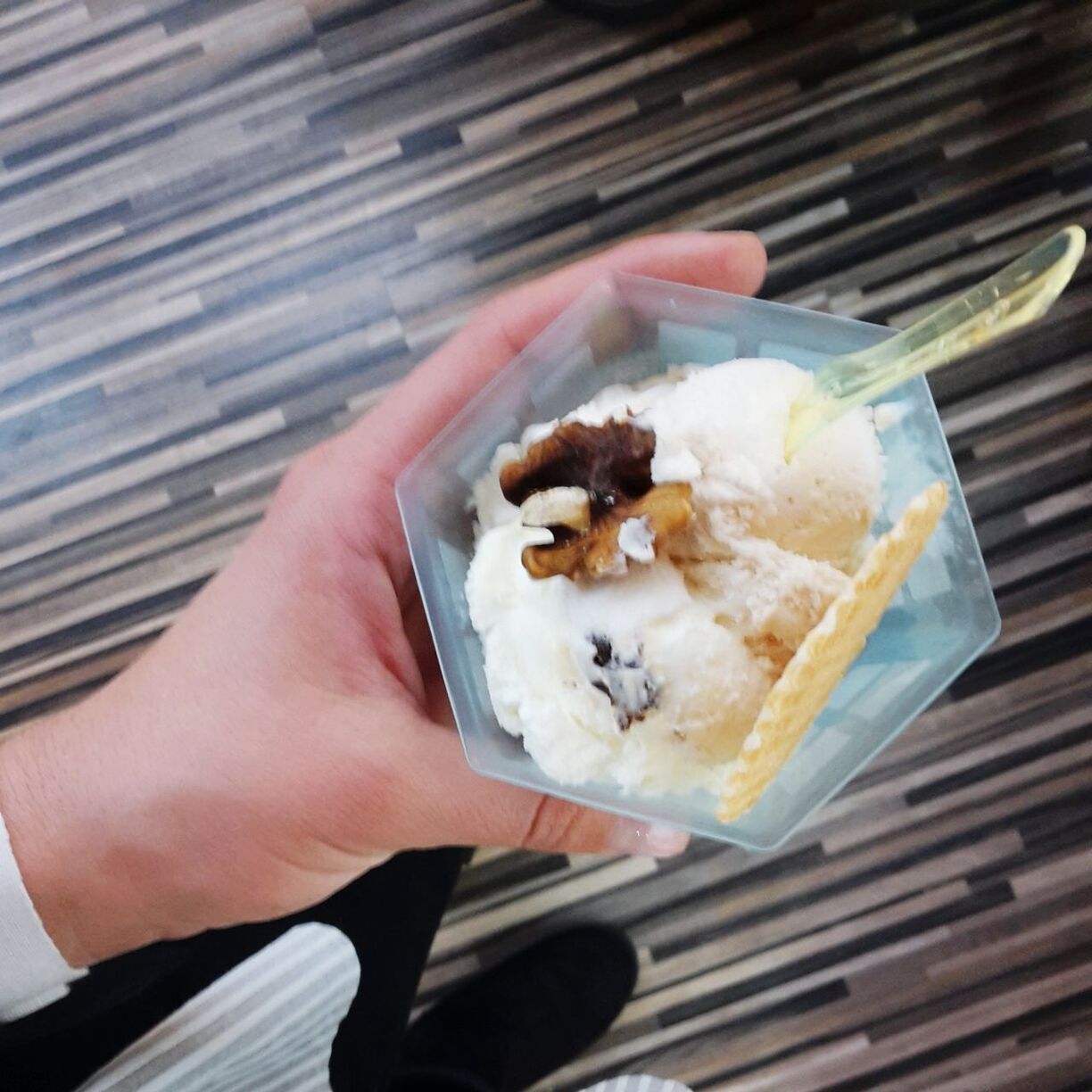 CLOSE-UP OF HAND HOLDING ICE CREAM CONE IN PLATE