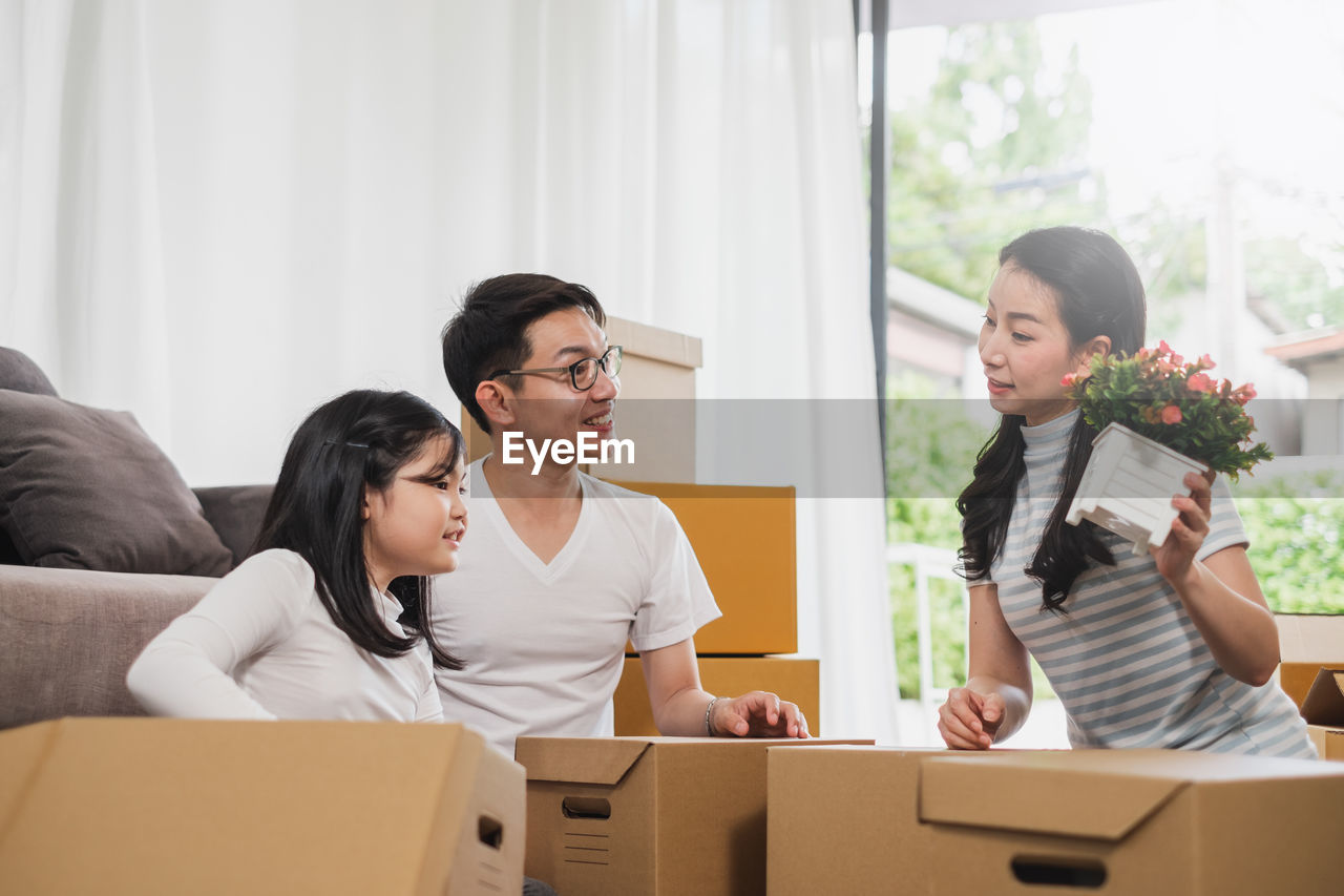 Smiling family packing cardboard while sitting at home