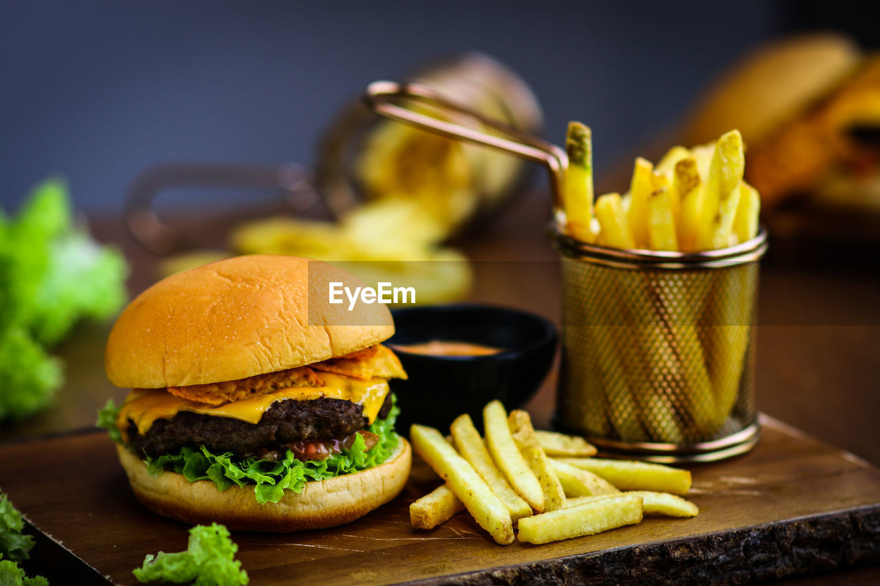 Close-up of burger with french fries served on wooden table