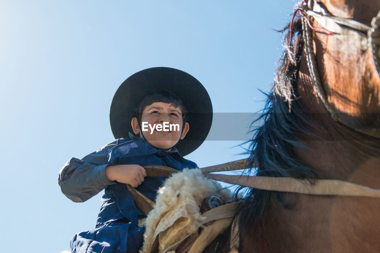 Low angle view of boy wearing hat against sky