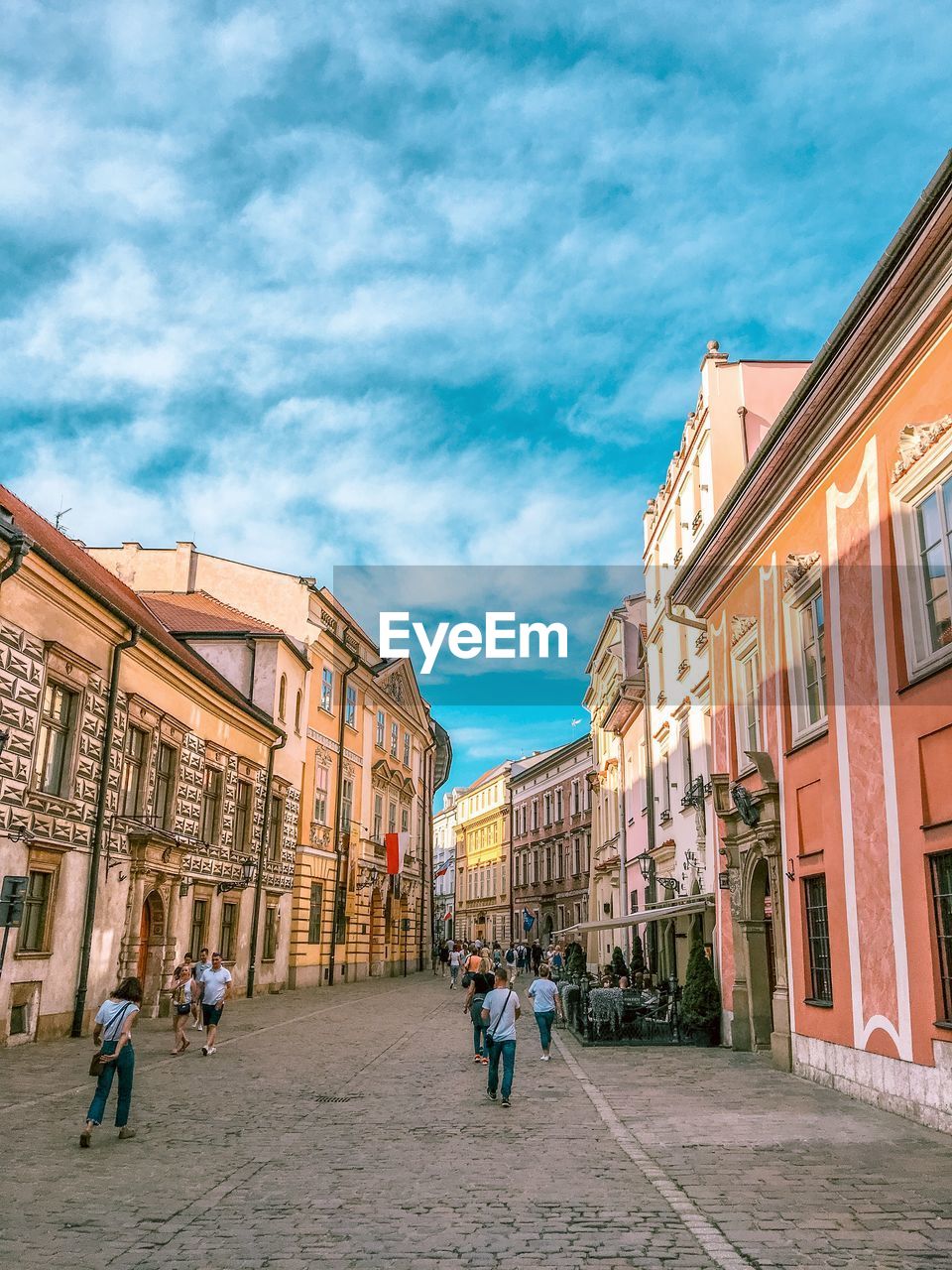 People walking on street amidst buildings in city against sky