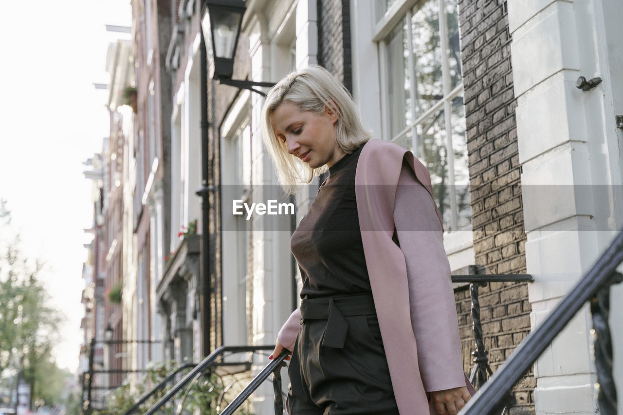 Side view of young woman standing in front of building