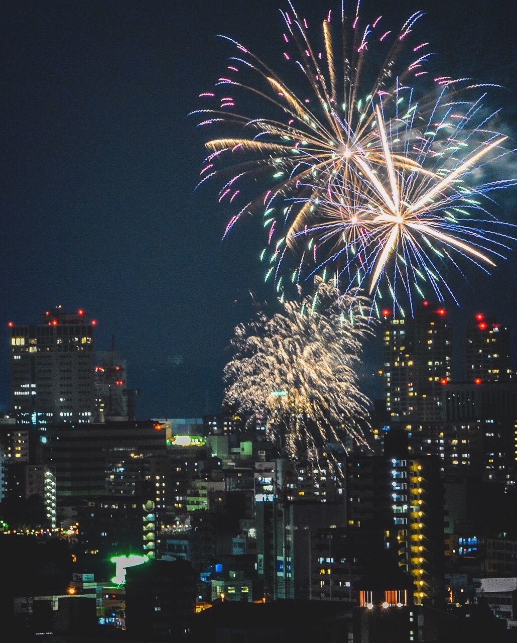 Fireworks exploding over city against sky