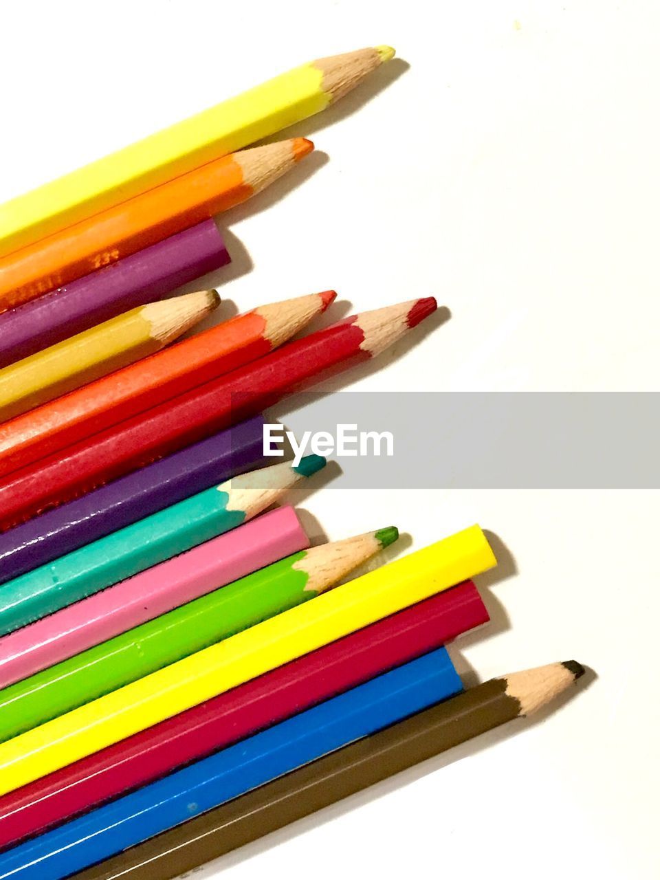 CLOSE-UP OF MULTI COLORED PENCILS AGAINST WHITE BACKGROUND