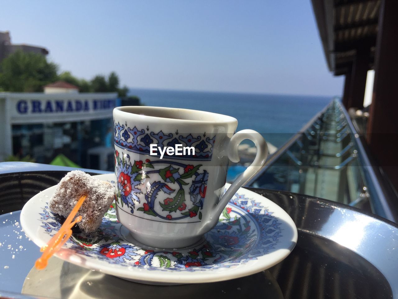 Close-up of coffee cup with sweet food on table against sea