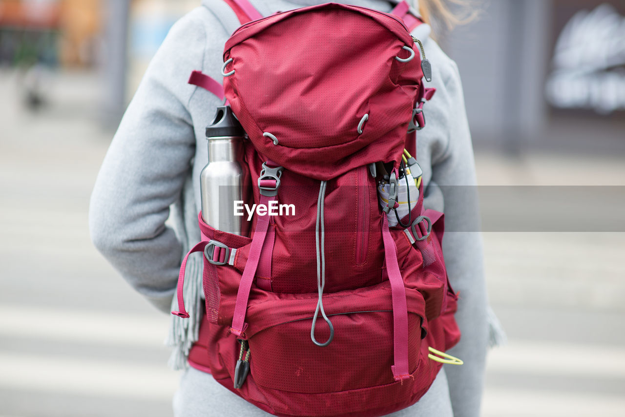 Rear view of woman carrying maroon backpack in city