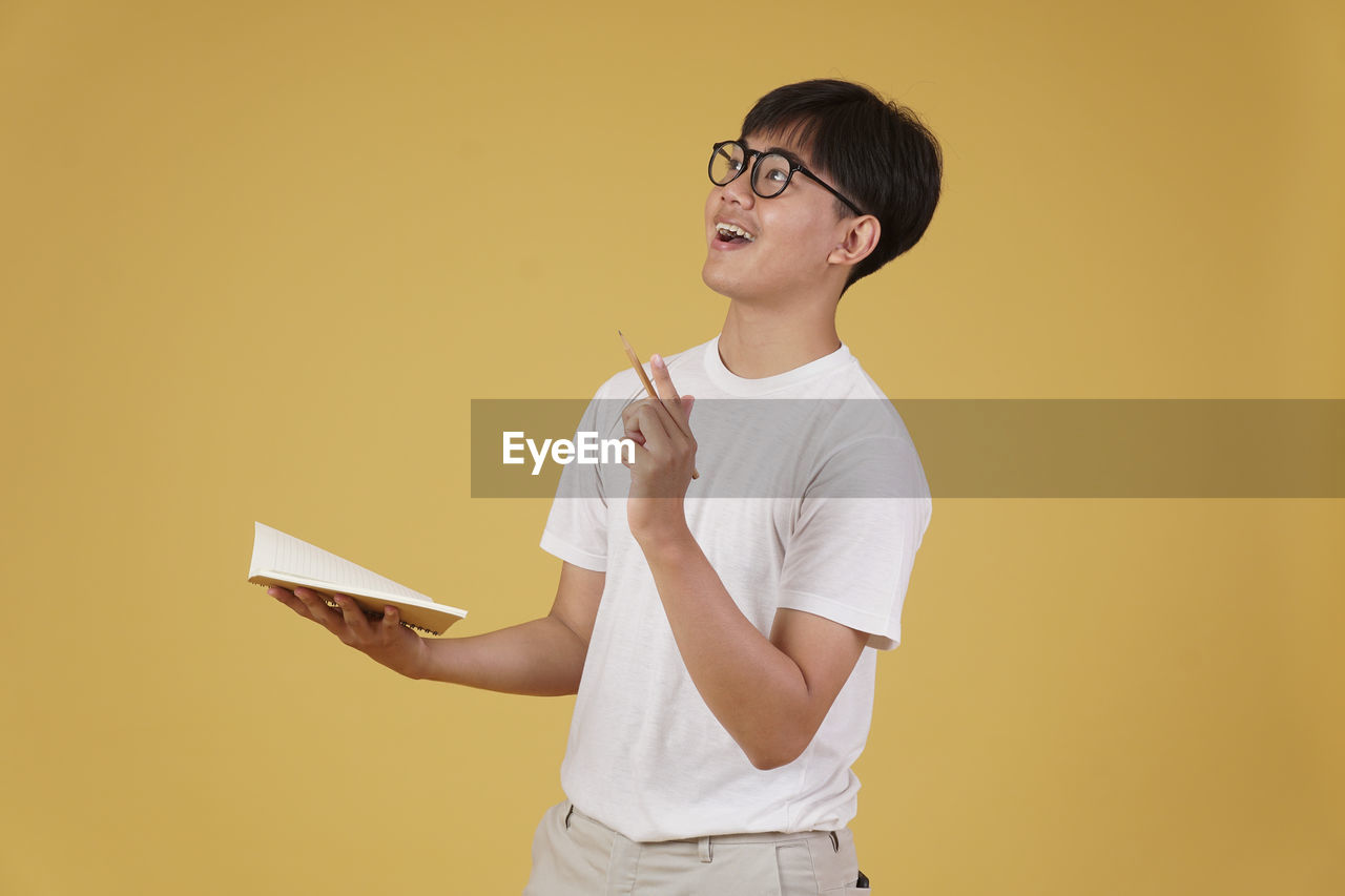 FULL LENGTH OF A BOY STANDING AGAINST YELLOW