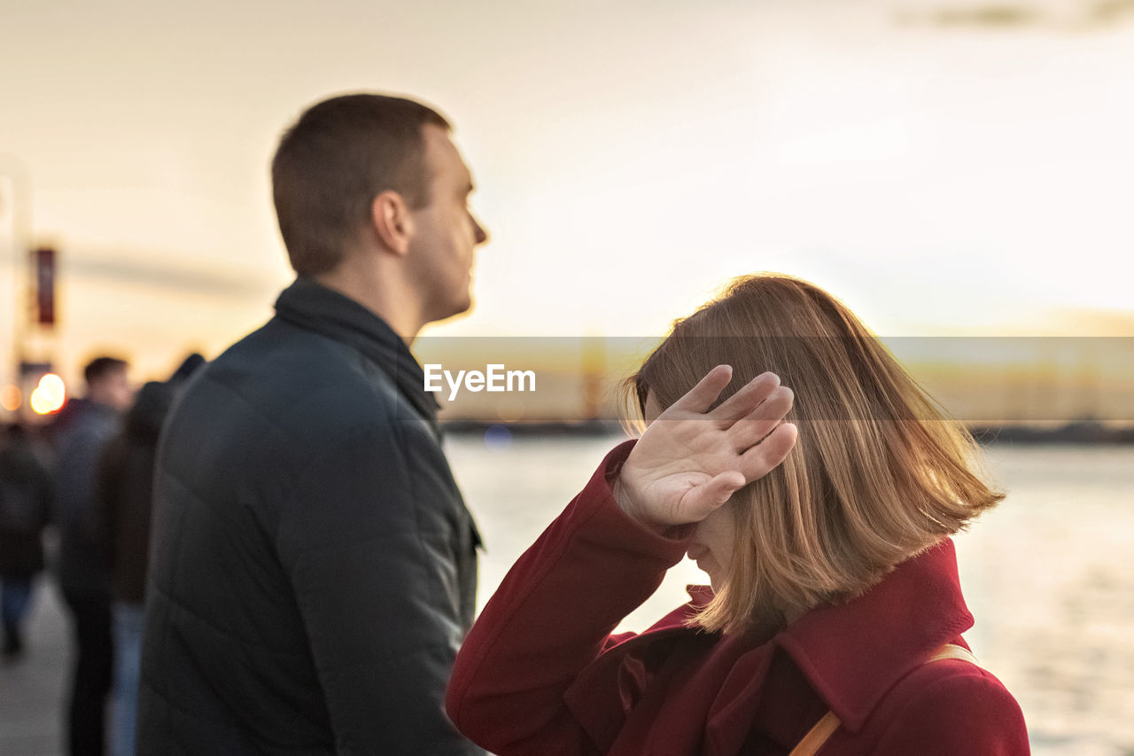 Young couple man and woman in a quarrel, on the embankment of the river in the city 