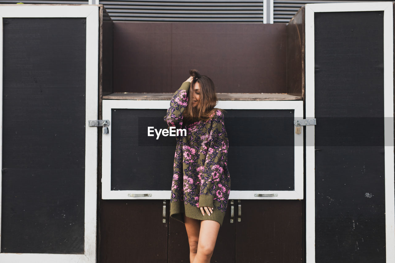 Young woman smiling while standing against doors