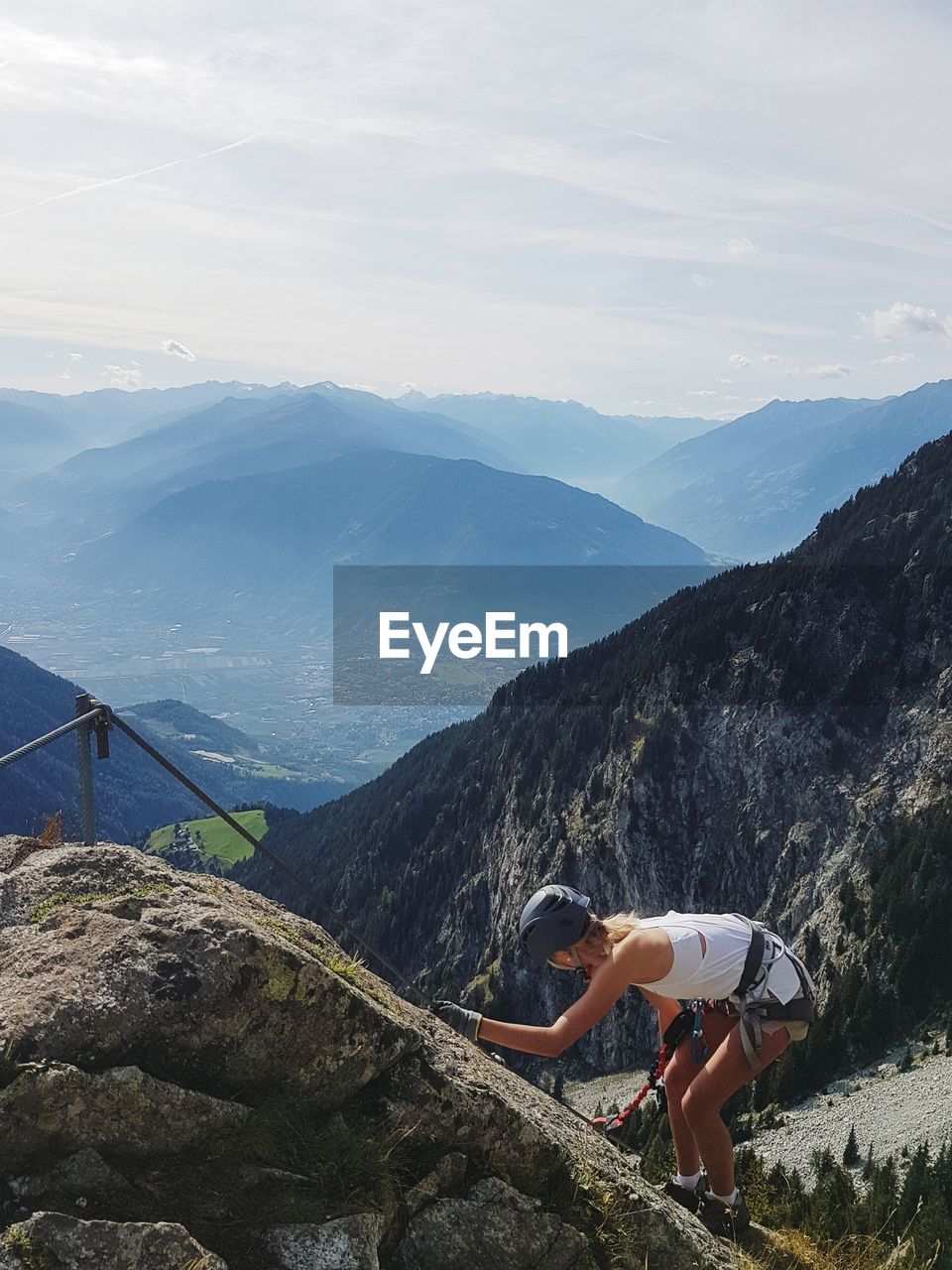 Full length of woman climbing rocks in a mountain at heini-holzer-klettersteig