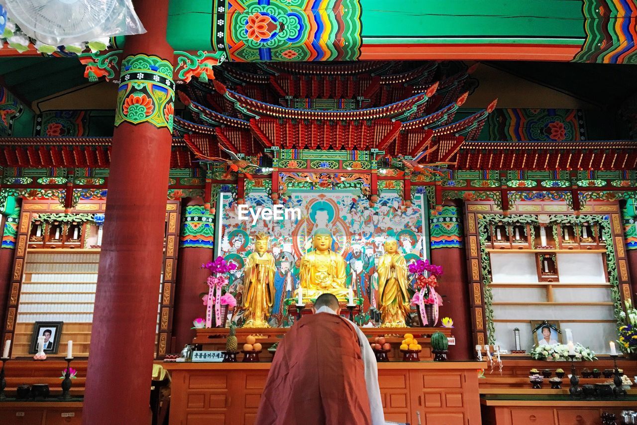 Rear view of a woman praying at buddha