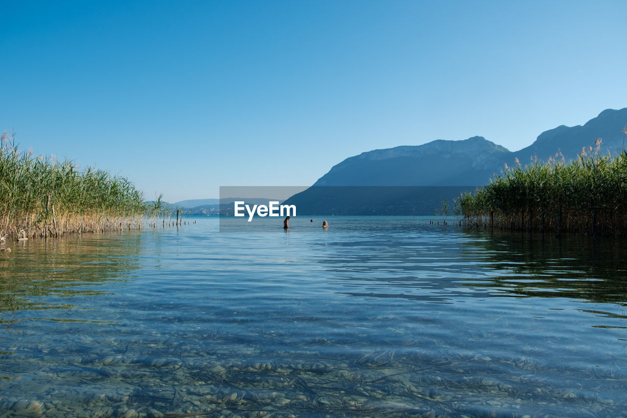 SCENIC VIEW OF LAKE BY MOUNTAINS AGAINST CLEAR BLUE SKY