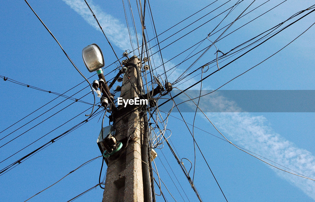 Low angle view of electricity pylon against blue sky