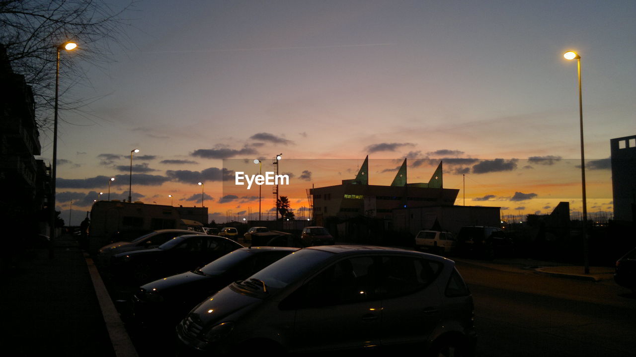 Cars parked on street against sky during sunset